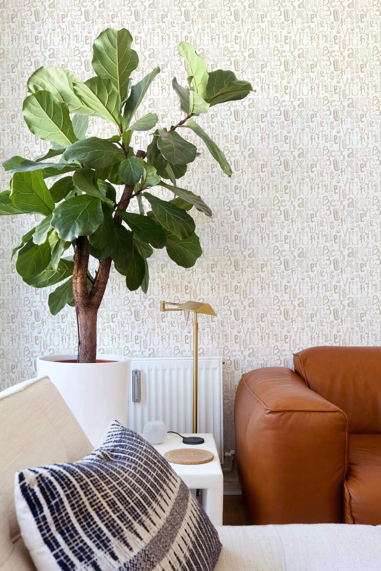 Alphabet wallpaper in a room setting: hand-drawn beige letters and numbers overlap in a busy white-ground print