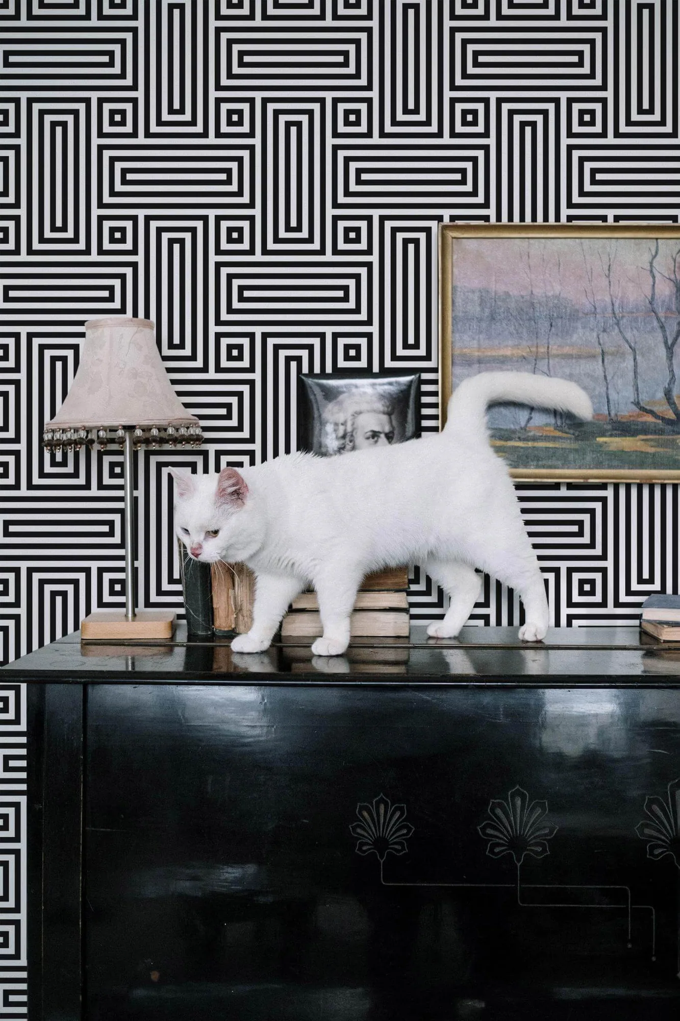 Black and white retro geometric wallpaper in a room setting: bold black maze-like lines turn at right angles on white