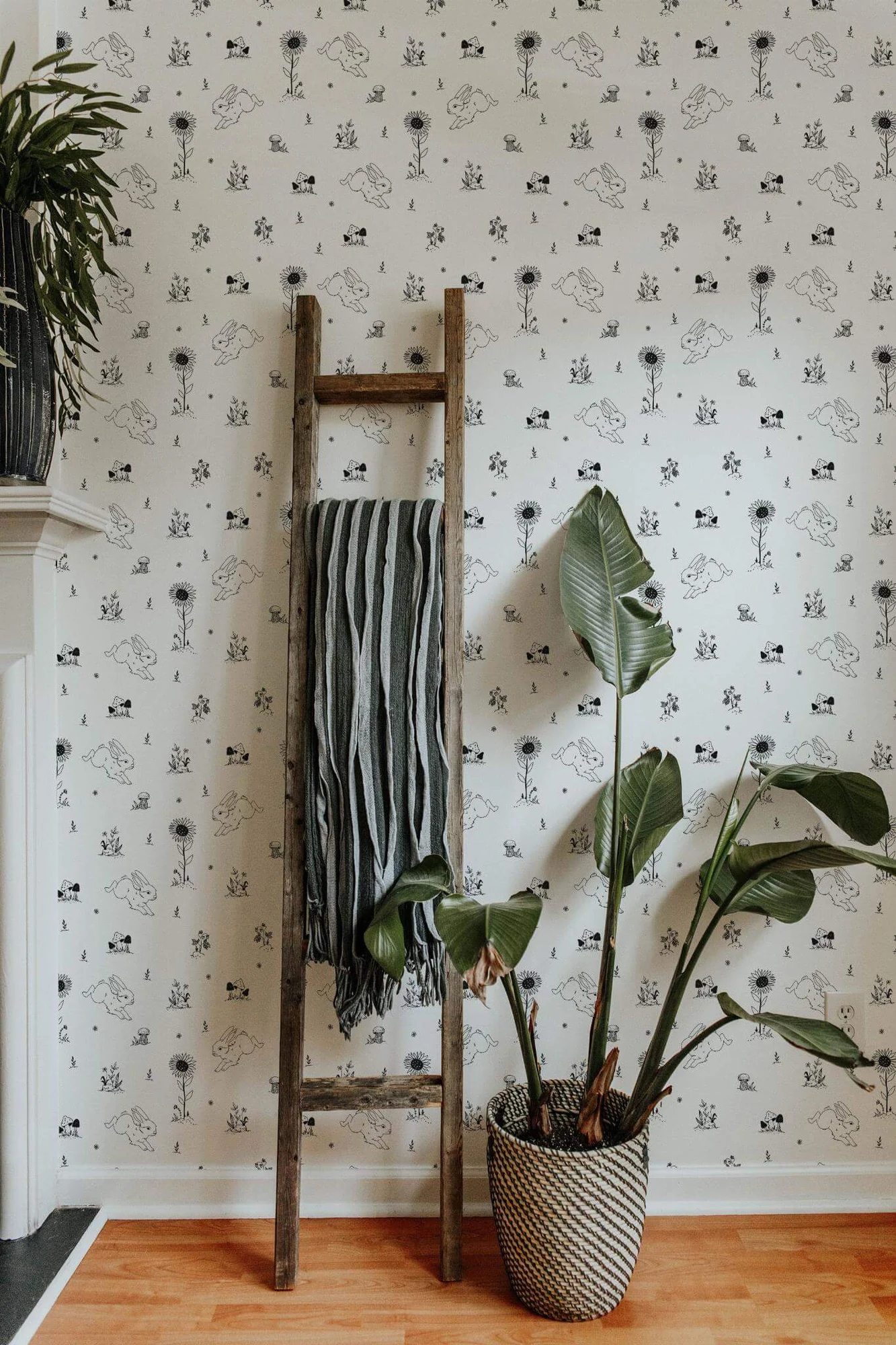 Bunny nursery wallpaper in a room setting: black-and-white woodland rabbits and small botanical motifs