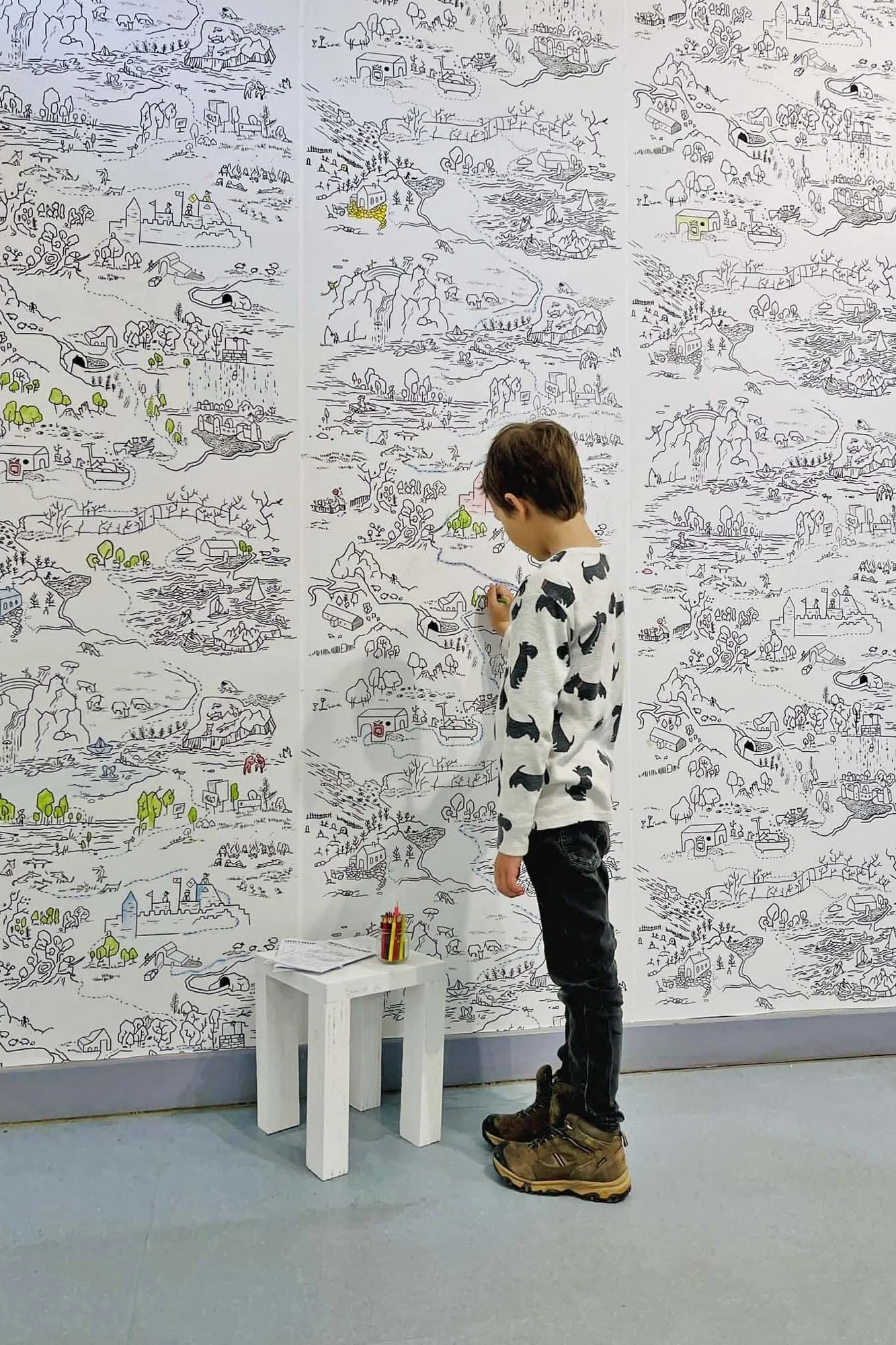 Fairytale map paintable wallpaper in a room setting: a black-and-white fairytale map made to be colored in by little artists