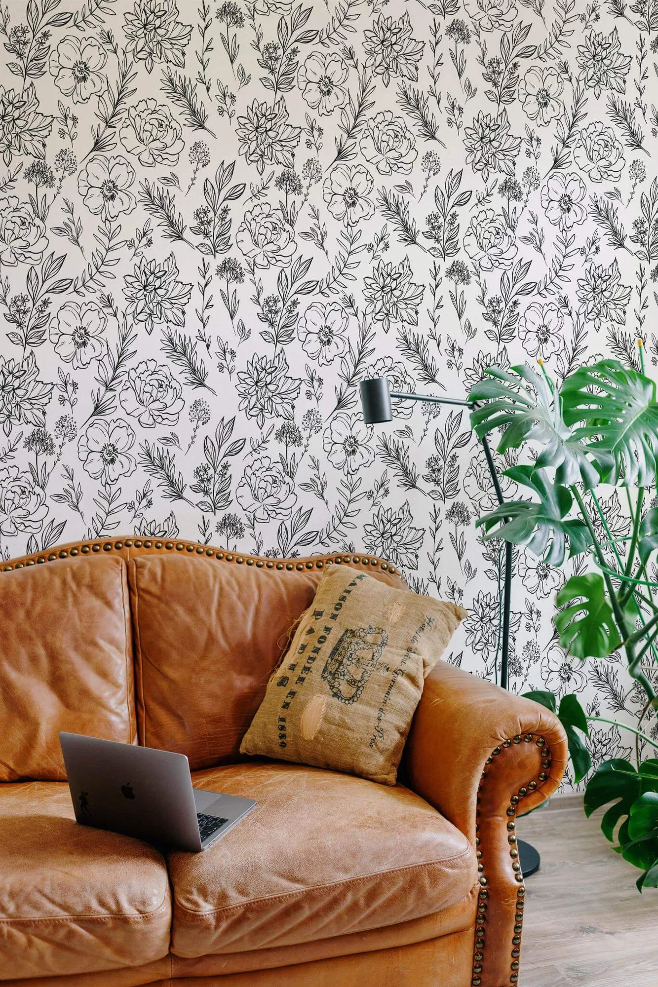 Floral garden wallpaper in a room setting: black line-drawn flowers and leafy stems in a full white-ground repeat