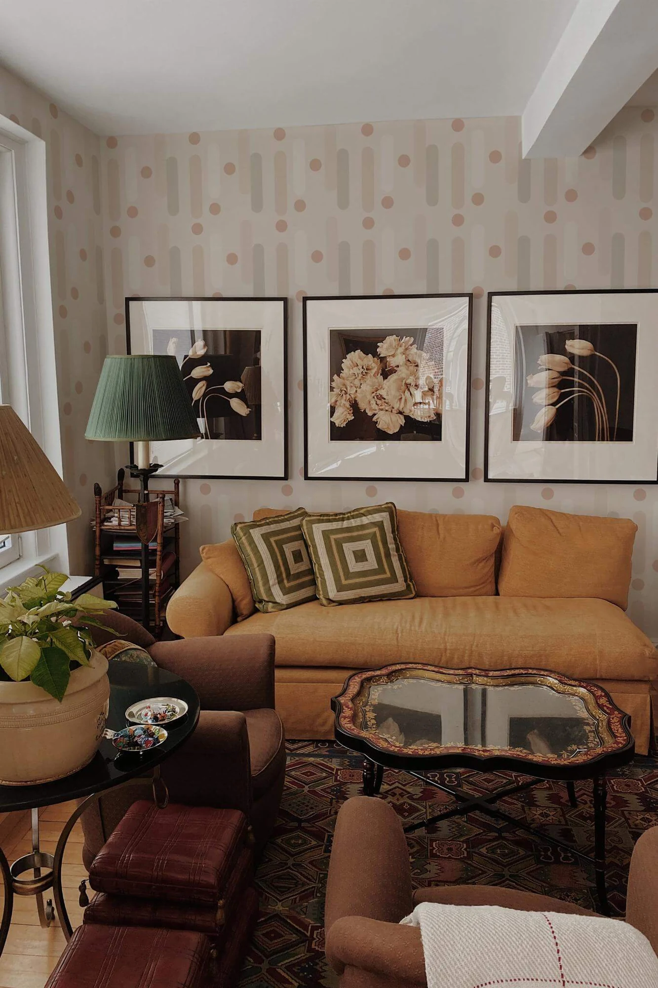 Neutral geometric wallpaper in a warm living room with a tan sofa: rounded vertical forms and small circles in a soft warm palette