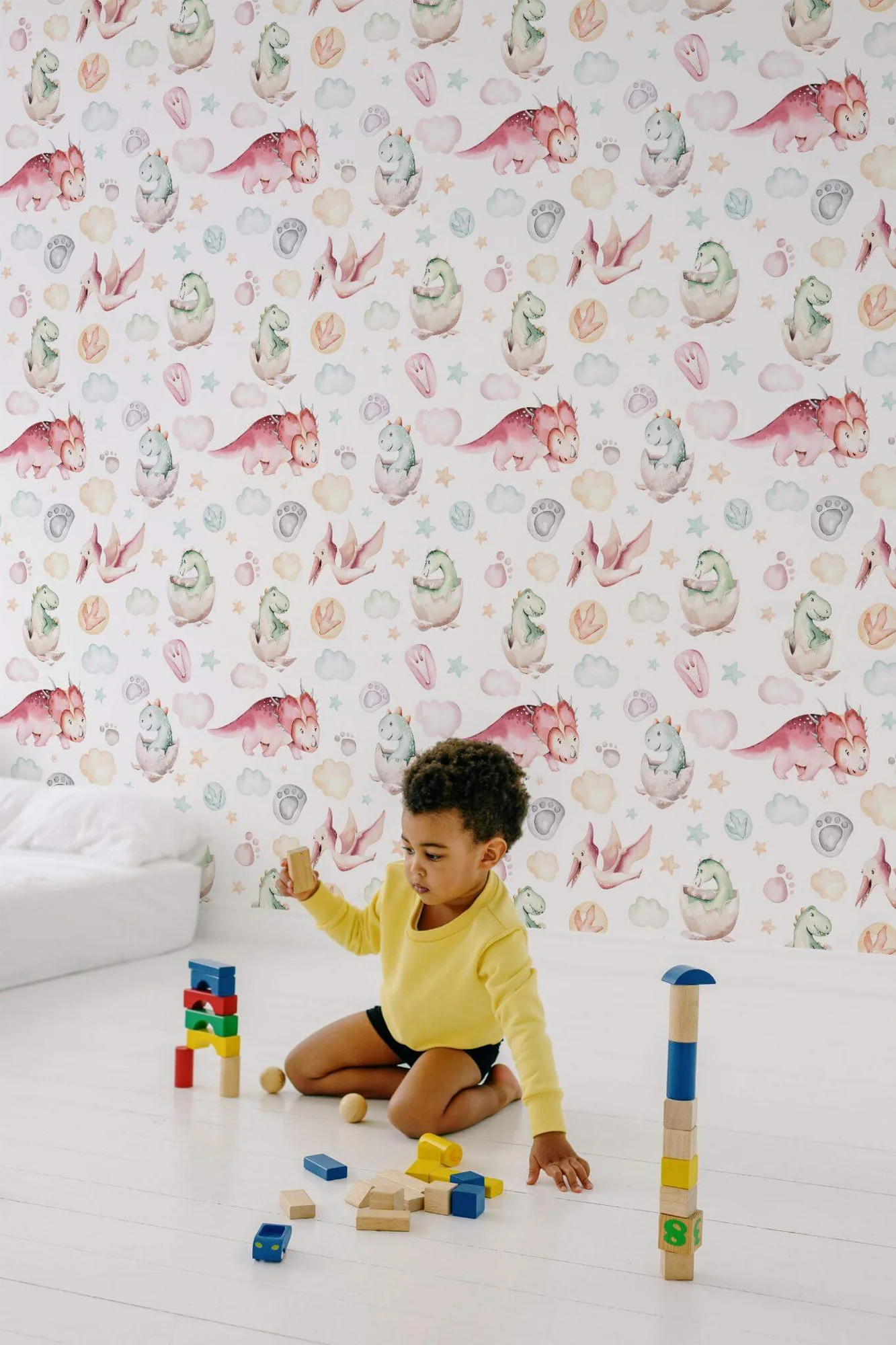 Pastel seamless dinosaur wallpaper in a room setting: soft watercolor dinosaurs and hatchlings drifting among clouds in gentle pastels